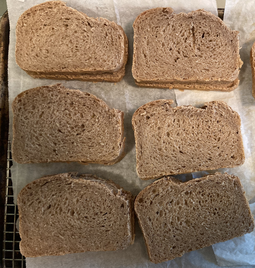 Slices of whole wheat bread on a pan for freezing.