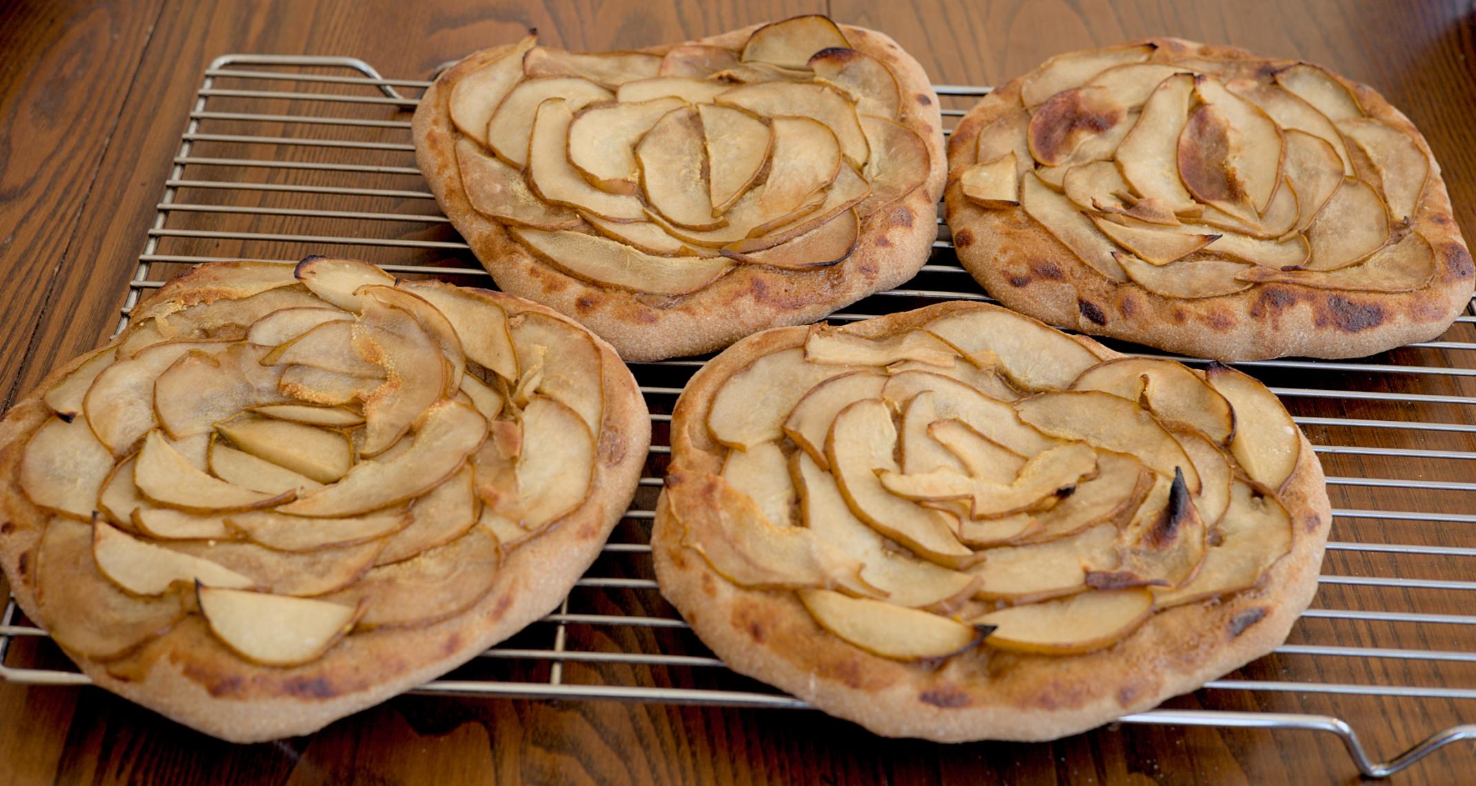 Four homemade pear pizzas on a cooling rack.